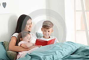 Mother and her children reading book together at home