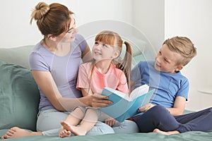 Mother and her children reading book together at home