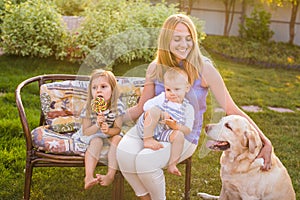 Mother and her children Relaxing In Garden With Pet Dog. Happy family playing with their labrador retriever dog on a