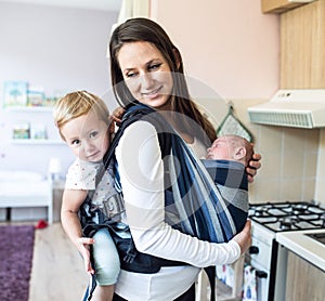 Mother with her children in sling and baby carrier