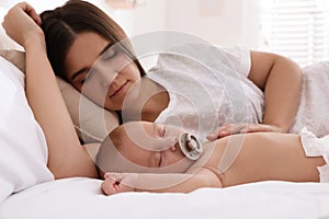 Mother with her cute baby sleeping in bed at home