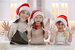Mother and her cute little children having fun while making Christmas cookies in kitchen