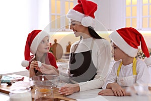 Mother with her cute little children making Christmas cookies in kitchen
