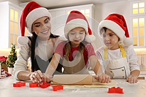 Mother and her cute little children making Christmas cookies in kitchen