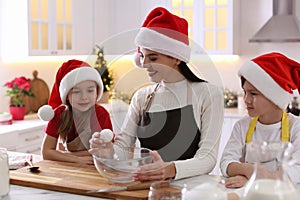 Mother with her cute little children making Christmas cookies in kitchen