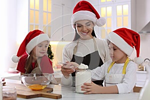 Mother with her cute little children making Christmas cookies in kitchen