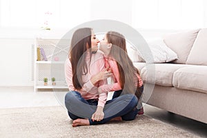 Mother with her cute little daughter sitting on the floor.