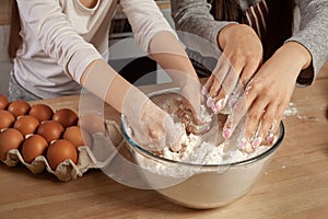 Mother and her daughter are baking a bread and having fun at the kitchen.