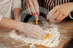 Mother and her daughter are baking a bread and having fun at the kitchen.