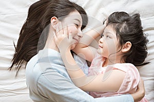 Mother and her daughter child girl hugging and Stroking her mom in the bedroom .Happy Asian family. photo