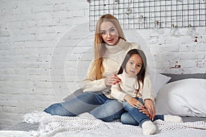Mother and her daughter child girl playing and hugging on bed