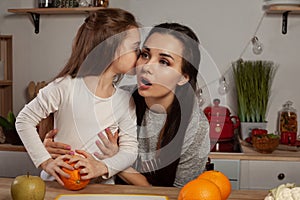 Mother and her daughter are doing a fruit cutting and having fun at the kitchen.