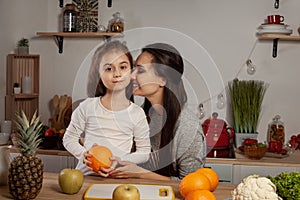 Mother and her daughter are doing a fruit cutting and having fun at the kitchen.