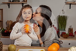 Mother and her daughter are doing a fruit cutting and having fun at the kitchen.