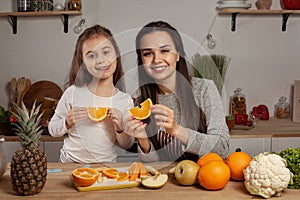 Mother and her daughter are doing a fruit cutting and having fun at the kitchen.