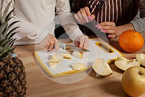 Mother and her daughter are doing a fruit cutting and having fun at the kitchen.