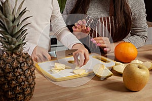 Mother and her daughter are doing a fruit cutting and having fun at the kitchen.