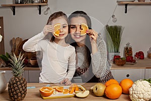 Mother and her daughter are doing a fruit cutting and having fun at the kitchen.