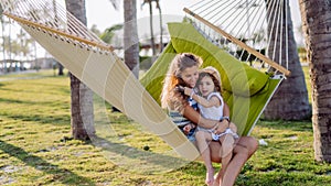 Mother with her daughter enjoying holiday in exotic country, lying in hammock.