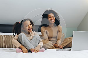 Mother with her daughter at home, watching TV