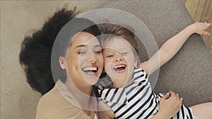 Mother and her daughter lie on the couch and take a selfie. Top view of happy family are smiling to the camera