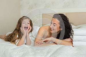 Mother and her daughter playing and hugging in the bed. Happy loving family. Happy mother& x27;s day.