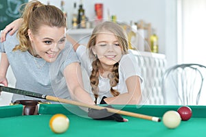 Mother with her daughter playing pool