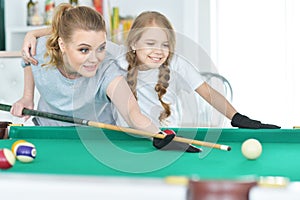 Mother with her daughter playing pool