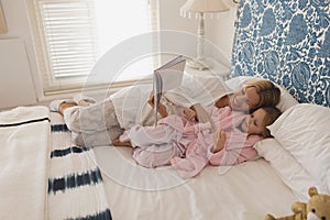 Mother with her daughter reading storybook in bedroom