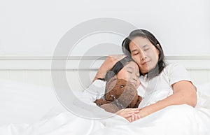 Mother and her daughter sleep on bed