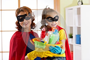 Mother and her daughter in Superhero costume. Mum and kid ready to house cleaning. Houseworking and housekeeping.