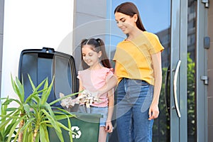 Mother and her daughter throwing paper into recycling bin