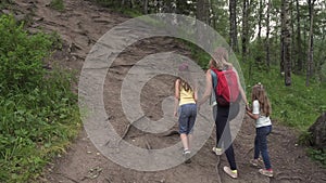 Mother with her daughters embarks on a journey. A family of tourists up the hill on the forest path