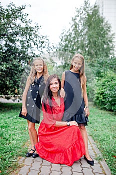 Mother and her daughters to school. Adorable little girls feeling very excited about going back to school