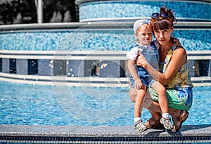 Mother in her fourties hugging her infant child outdoors in a park in a sunny day photo