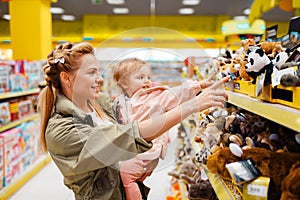 Mother with her girl choosing toys in kids store