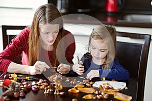 Mother and her kid making chestnuts creatures
