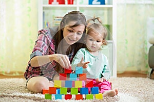 Mother and her kid play with toys indoors