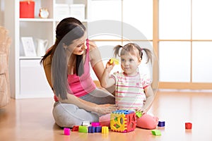 Mother and her kid playing with colorful logical sorter toy