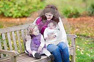 Mother with her kids on wooden bench in park