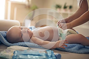 Mother with her little baby boy at home changing diapers.