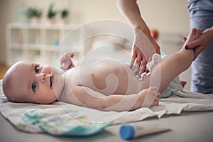 Mother with her little baby boy at home changing diapers.