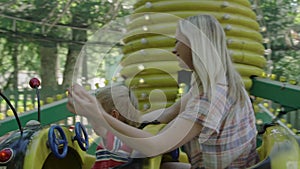 Mother and her little baby boy are riding on caterpillar in the amusement park 4k