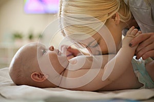 Mother and her little baby enjoying at home on bed.