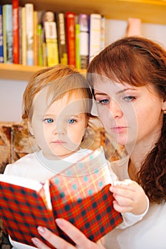 Mother with her little baby son reading book