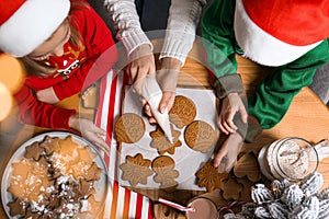 Mother and her little children decorating tasty Christmas cookies at wooden table, top view