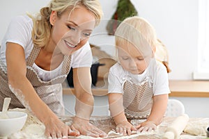 Mother and her little daughter cooking holiday pie or cookies for Mother`s day. Concept of happy family in the kitchen