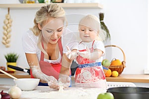 Mother and her little daughter cooking holiday pie or cookies for Mother`s day. Concept of happy family in the kitchen