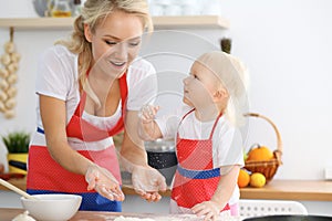 Mother and her little daughter cooking holiday pie or cookies for Mother`s day. Concept of happy family in the kitchen