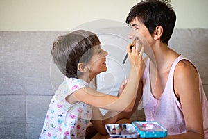 Mother and her little daughter doing make up for each other